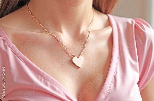 Close-up of a gold heart pendant on a woman wearing a white blouse. photo