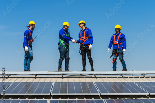 Group of professional solar engineer men team working on industrial roof photo