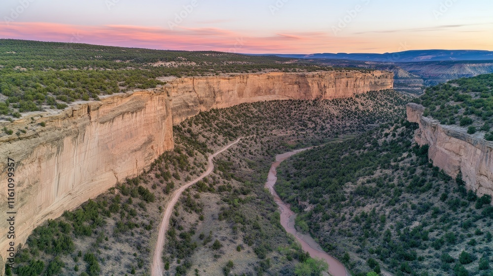 Aerial view of a canyon at sunset, showing a winding road and river. Aerial view of a canyon at sunset, showing a winding road and river.