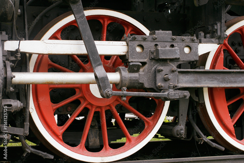 Close-Up View of a Steam Train's Red Spoked Wheels and Mechanical Parts Close-Up View of a Steam Train's Red Spoked Wheels and Mechanical Parts