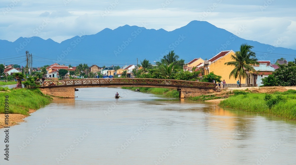 Naklejka premium Tranquil river scene with a small bridge, houses, mountains, and a lone boatman.