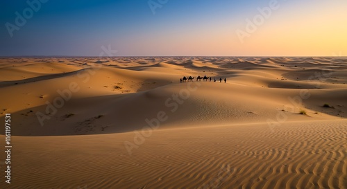 Stunning desert landscape.  Sunrise or sunset over dunes.  Camels and people travel.  Tourism.