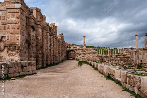 A stone walkway with a stone archway leading to a courtyard
