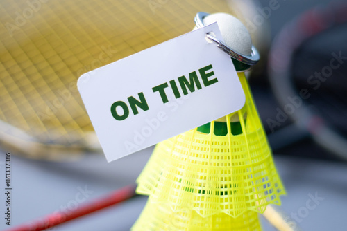 On time text printed on a white sheet and attached with a badminton cock - to represent a concept of punctual photo