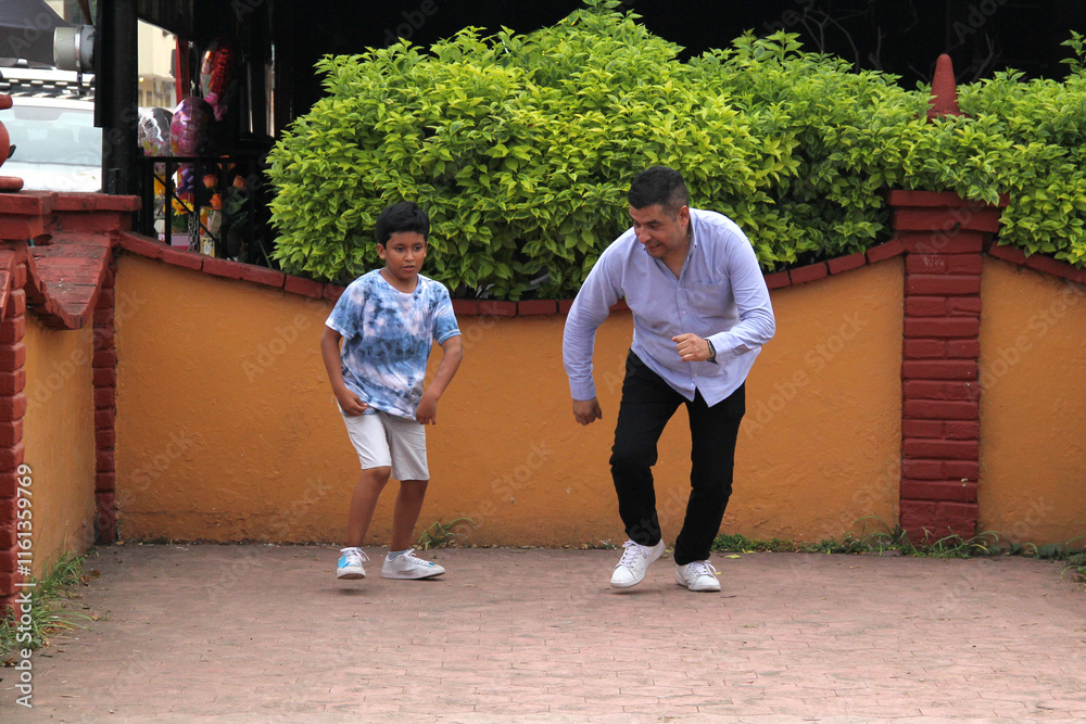 Obraz premium Latino dad and dark-skinned 9-year-old son play a speed race in the street, they have fun and are happy in poverty