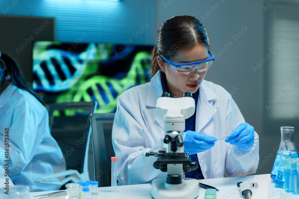 Female scientist using a microscope, conducting research in a modern lab with dna double helix displayed on screen