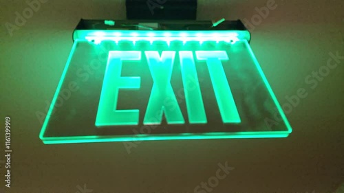 A bright green exit sign lights up a hallway, guiding the way to safety. The clear visibility of the sign ensures that anyone can find the exit easily during