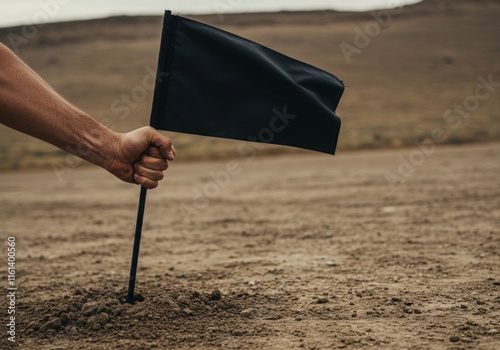 Hands gripping the handle of a black flag being planted into the ground, symbolizing achievement, success, and victory