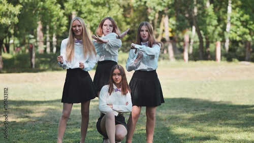 Four high school girls in uniform and lilac bow ties, striking a pose in a park to commemorate their first day back at school photo