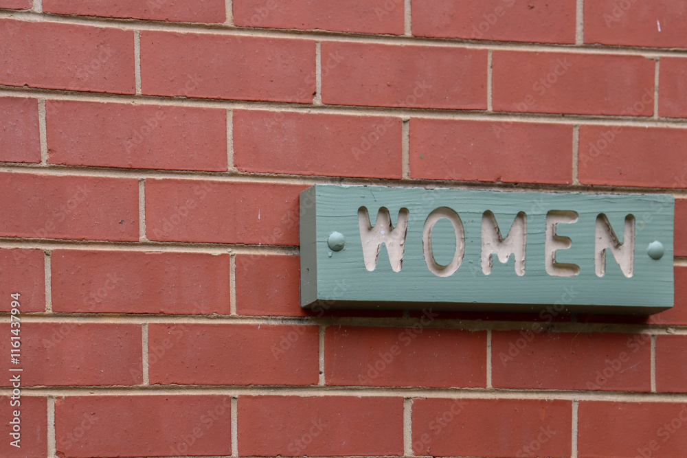 women sign on brick wall of public restroom women sign on brick wall of public restroom