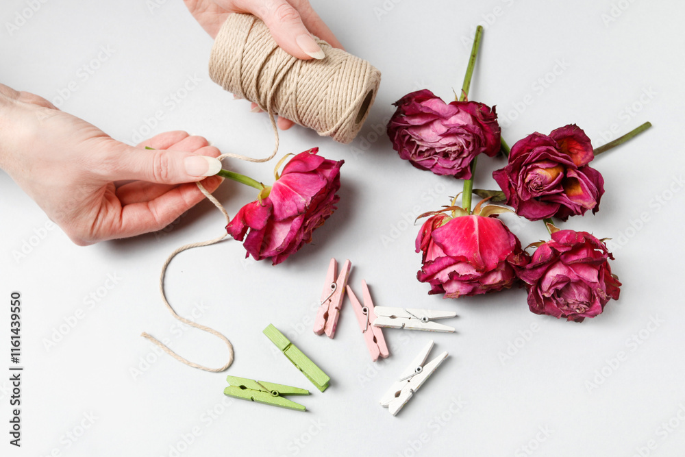 Florist at work: woman shows how to make a simple Valentine's Day decoration with semi-dry roses, string and clothes pegs. Step by step, tutorial.