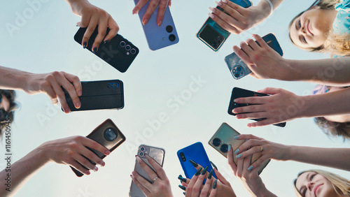 High school students with smartphones gathered in a circle under a summer sky