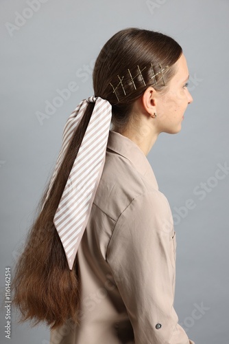 Teenage girl with stylish hair clips and bandana on light grey background photo