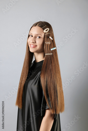 Teenage girl with stylish hair clips on light grey background photo