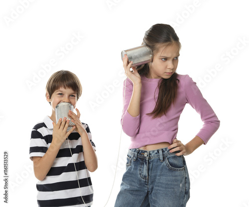 Girl and boy talking on tin can telephone against white background