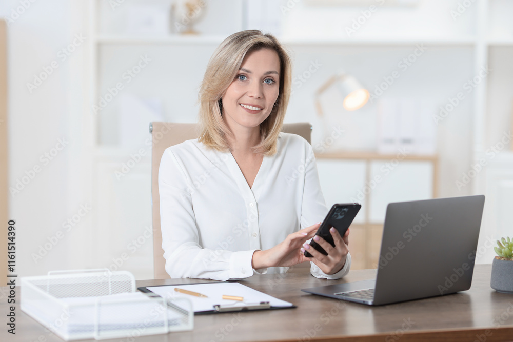 Businesswoman using smartphone at table in office Businesswoman using smartphone at table in office