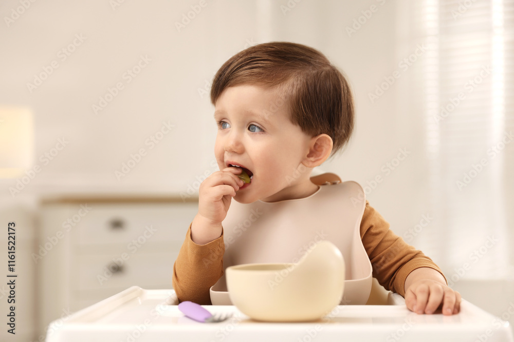 Cute little kid eating healthy baby food from bowl in high chair at home Cute little kid eating healthy baby food from bowl in high chair at home