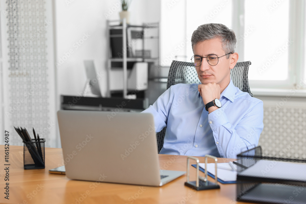 Middle aged man working with laptop at table in office Middle aged man working with laptop at table in office