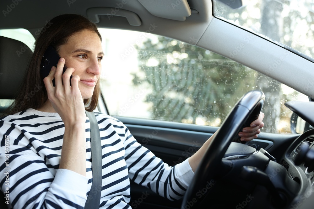 Fototapeta premium Driver talking on smartphone while driving modern car