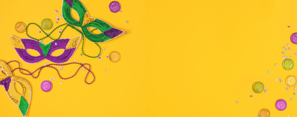 Top view of a beautiful composition of colorful masks, confetti, Mardi Gras decorations. Yellow Mardi Gras banner. Mardi gras holiday background