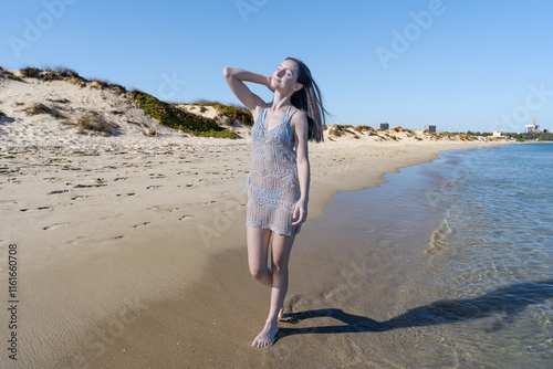 Chica joven muy a gusto y relajada en la playa junto al mar, con un sensacional día de vacaciones en verano soleado y con cielo azul. photo