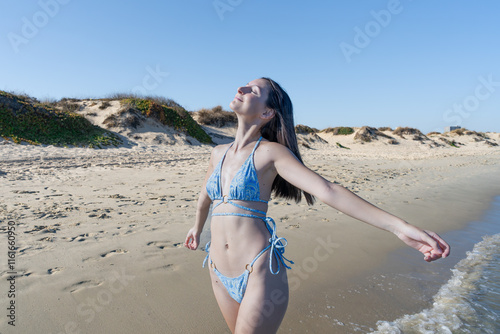 Chica joven muy a gusto y relajada en la playa junto al mar, con un sensacional día de vacaciones en verano soleado y con cielo azul. photo