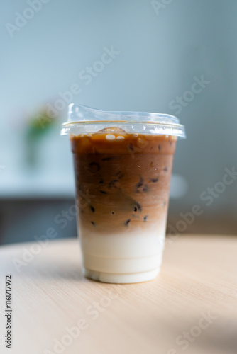 Cup of ice cafe latte with two layer, espresso and fresh milk on table