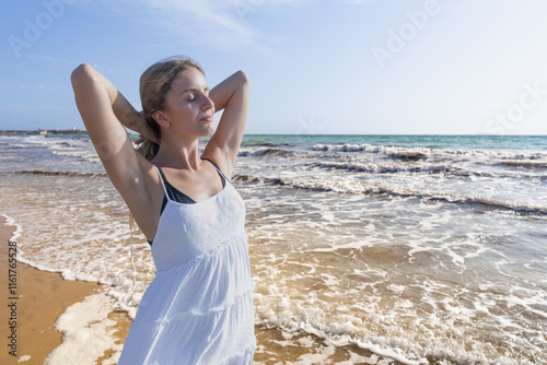 Mujer joven muy a gusto en la playa con un sensacional día soleado con cielo azul de vacaciones en verano. photo