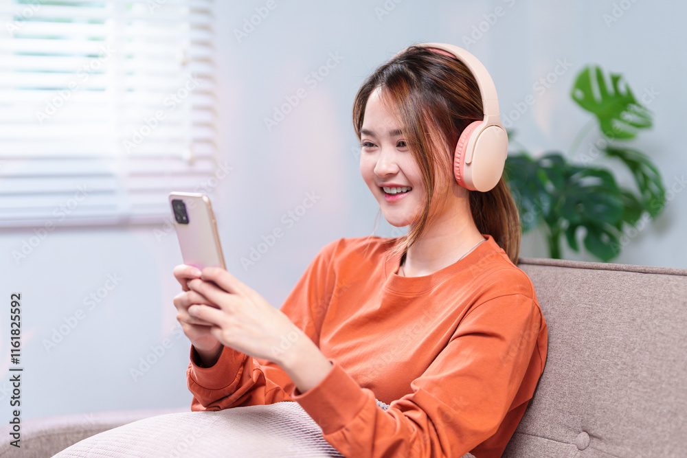 A young woman wearing headphones, smiling while using her smartphone, immersed in an engaging mobile experience A young woman wearing headphones, smiling while using her smartphone, immersed in an engaging mobile experience