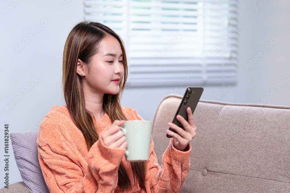 A woman multitasking, holding a mug of coffee in one hand and checking her smartphone with the other, seated comfortably on a sofa A woman multitasking, holding a mug of coffee in one hand and checking her smartphone with the other, seated comfortably on a sofa