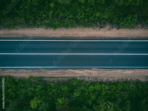 Aerial view of an empty road in lush green forest landscape