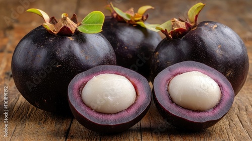 A close-up of whole and halved mangosteens, highlighting their deep purple rind and white flesh, set on a wooden surface photo