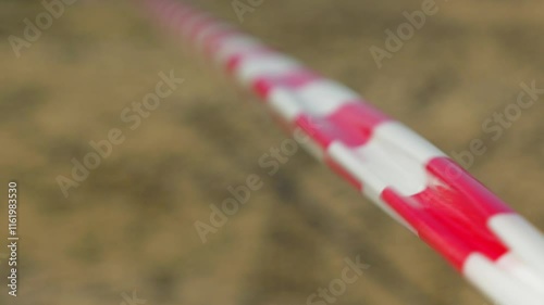 A close-up of a red and white striped tape, used for marking off areas, stretches into the blurred background. Usually such tape is used to cordon off areas. The wind ruffles the red and white ribbon.