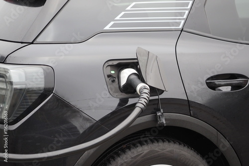 A black electric vehicle, EV, charging at a car charging point