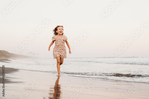 Little girl running by seashore beach on summer evening photo