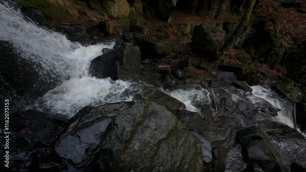 Lumsdale falls streaming on big rocks in a steep-sided gorge in Derbyshire, UK