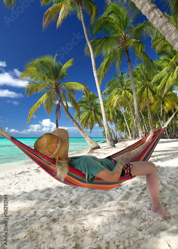 woman relaxing on a colorful hammock on a tropical beach with palms and turquoise sea photo