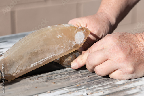 Close up of male man's hands cutting a raw Montana moss agate with a wet rock or tile saw to create slabs for cabbing, lapidary work and jewelry making and geology study photo