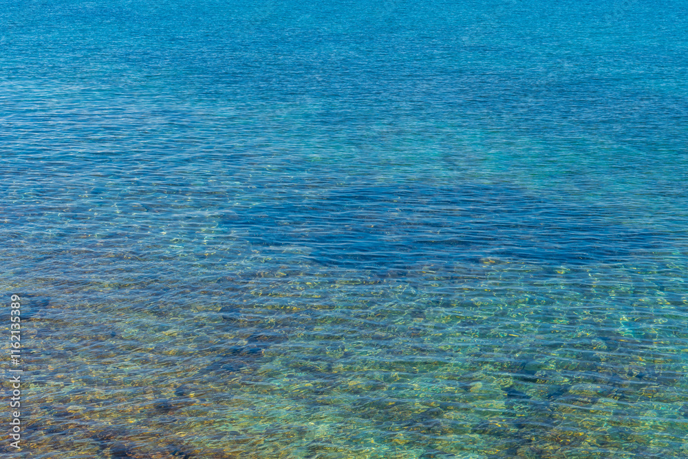 Obraz premium Crystal clear water gently washing over rocks in mallorca, spain