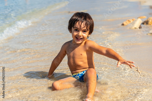 Happy child playing on the shore of estanys beach, mallorca, spain photo