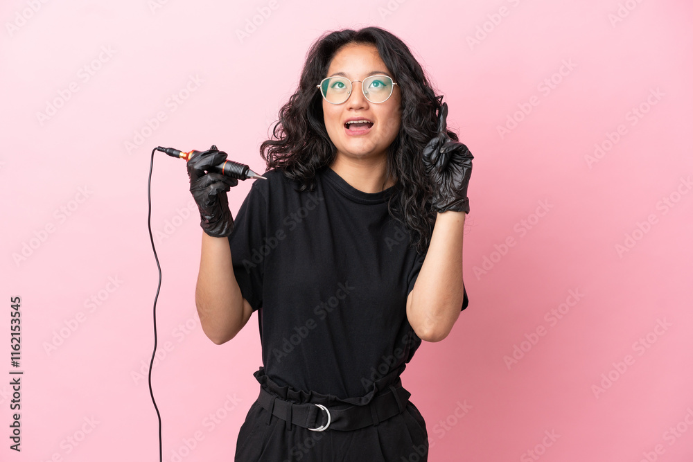 Tattoo artist asian woman isolated on pink background thinking an idea pointing the finger up Tattoo artist asian woman isolated on pink background thinking an idea pointing the finger up