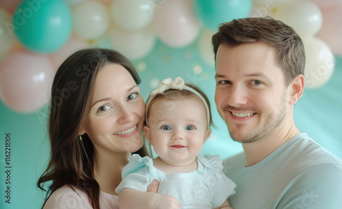 Parents smile lovingly while holding their baby, framed by pastel balloons, while another family enjoys outdoor bike rides, filling the scene with happiness and activity. photo