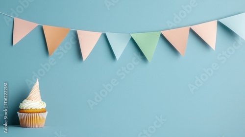 A colorful cupcake sits beside pastel bunting against a blue background, creating a festive and cheerful atmosphere.