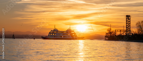 Passagierschiff bei Sonnenuntergang am See mit Aussichtsturm und ruhiger Wasseroberfläche photo