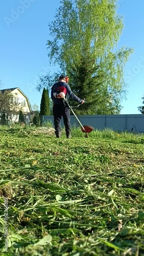 a man mows the grass in the garden. vertical video