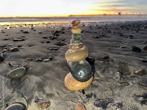 Tall Tower of Stacked Rocks on Shore at Sunset