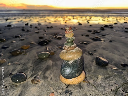 Tall Tower of Stacked Rocks on Shore at Sunset