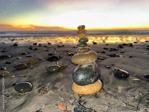 Tall Tower of Stacked Rocks on Shore at Sunset