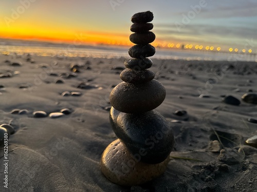 Tall Tower of Stacked Rocks on Shore at Sunset