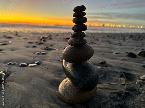 Tall Tower of Stacked Rocks on Shore at Sunset